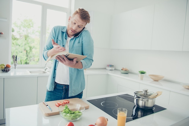 Aantrekkelijke roodharige man in de keuken die probeert te koken