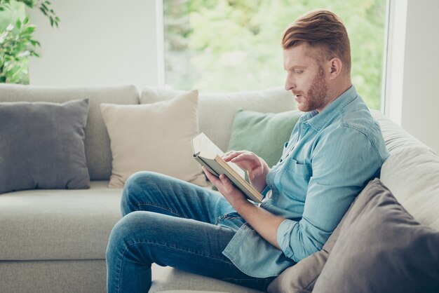 Aantrekkelijke roodharige man thuis op de bank