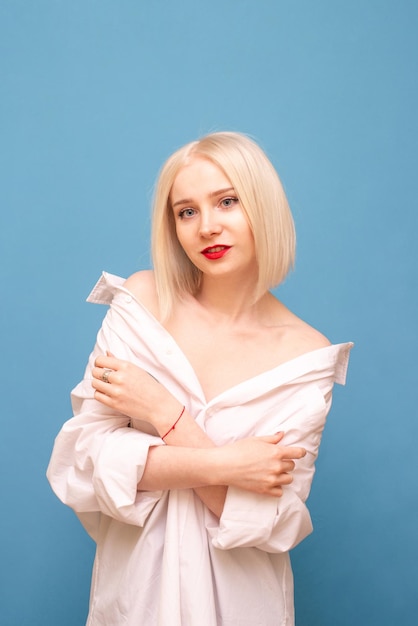 Aantrekkelijke sexy vrouw met blond haar en rode lippen staat op een blauwe achtergrond