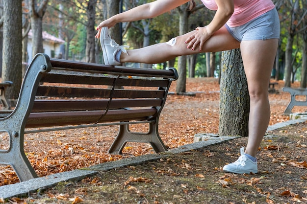 Aantrekkelijke sportieve vrouw die in een park opwarmt Mooi meisje die opwarmingsoefeningen in een park doet