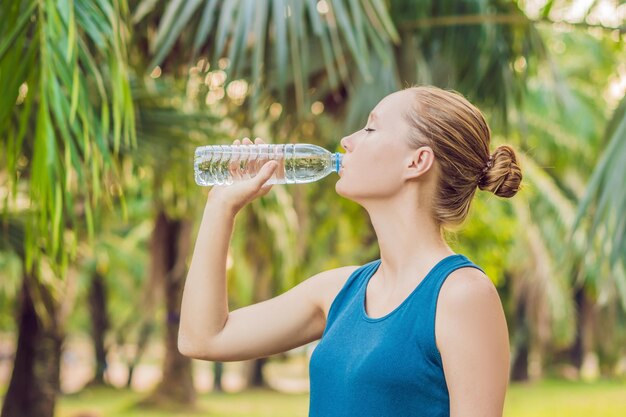 Aantrekkelijke sportieve vrouw drinkwater uit een fles na het joggen of hardlopen