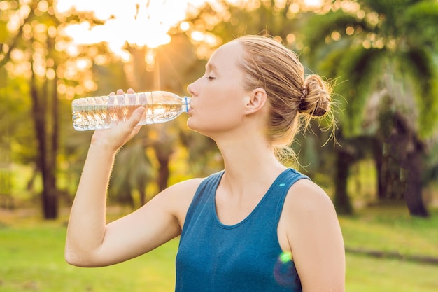 Aantrekkelijke sportieve vrouw drinkwater uit een fles na het joggen of hardlopen.