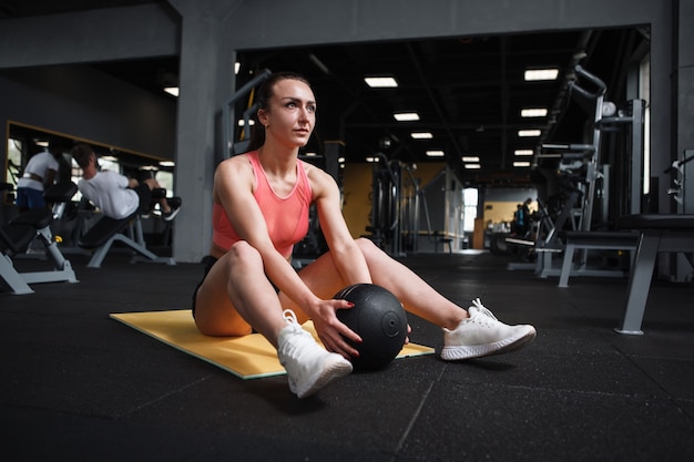 Aantrekkelijke sportvrouw die sit-ups doet met medicijnbal