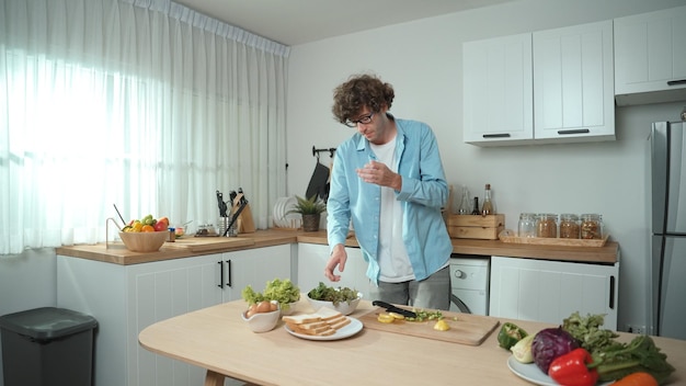 Aantrekkelijke vader beweegt zich naar muziek terwijl hij eten kookt en de lunch bereidt Pedagogie