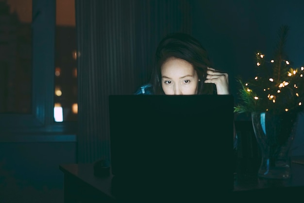 Aantrekkelijke vermoeide brunette vrouw van middelbare leeftijd met behulp van laptop thuis werken in de nacht