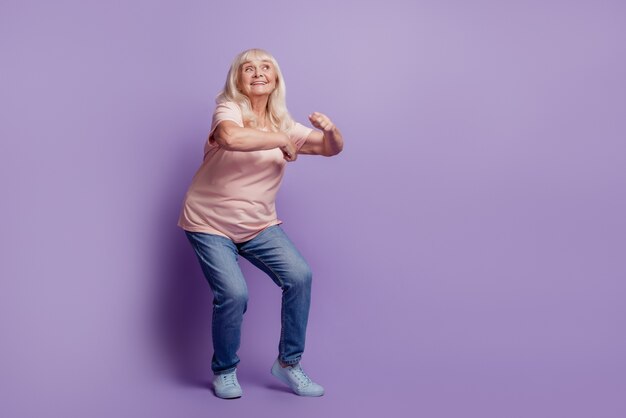 Foto aantrekkelijke volwassen feestliefhebber dame dansen op paarse achtergrond