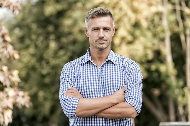 Aantrekkelijke volwassen man Zelfverzekerde man knappe man buiten mannelijke schoonheid en mode zakenman in casual kleding knappe man natuur achtergrond kopie ruimte Rust en ontspannen zonnige lentedag