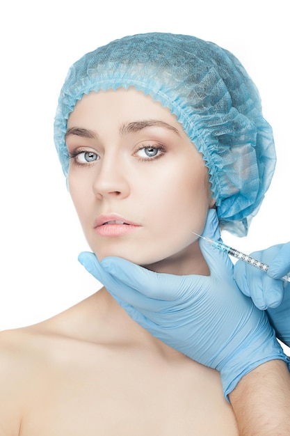 Aantrekkelijke vrouw bij plastische chirurgie met spuit in haar gezicht op witte achtergrond