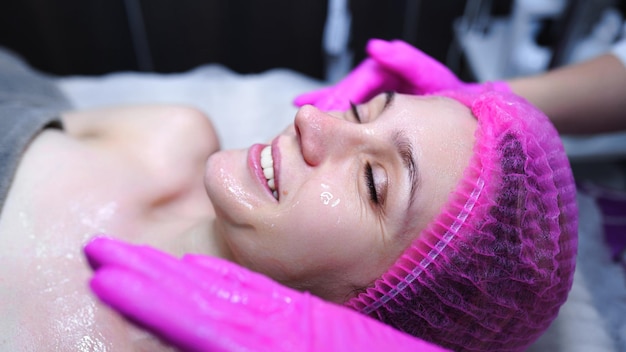 Aantrekkelijke vrouw bij spa health club krijgt een gezichtsmassage Schoonheidsspecialiste doet massage van gezicht nek en schouders ofbeautiful jonge vrouw bij luxe schoonheidssalon