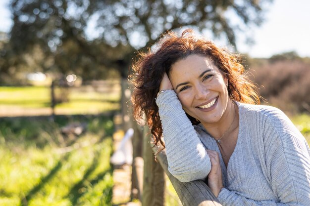 Foto aantrekkelijke vrouw camera kijken en lachend met positieve emotie. natuur achtergrond