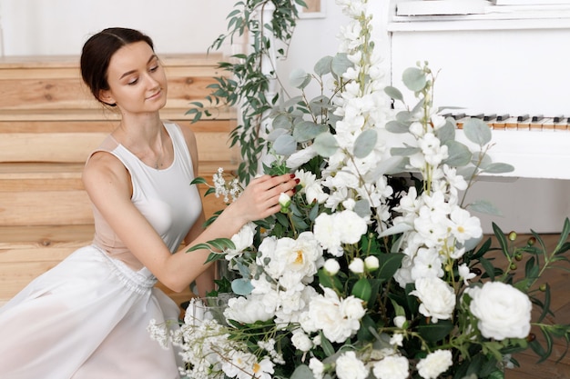 Aantrekkelijke vrouw dichtbij bloemen met piano