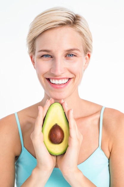 Aantrekkelijke vrouw die de helft van een avocado toont