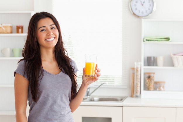 Aantrekkelijke vrouw die een glas jus d&#39;orange houdt terwijl status