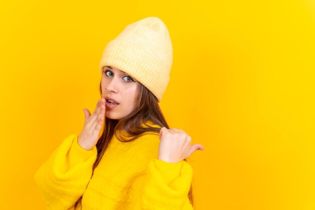 Aantrekkelijke vrouw die lacht wijzende vingers naar kopie ruimte op gele achtergrond wollen trui