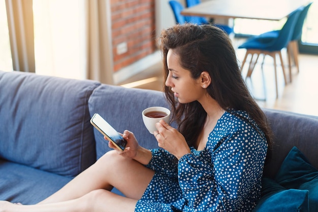 Aantrekkelijke vrouw die tablet in moderne woonkamer thuis gebruikt die vrije tijd doorbrengt met chatten op sociale media