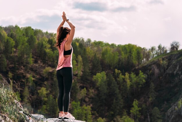 Aantrekkelijke vrouw die yoga doet. Gezonde levensstijl. De concentratie van het lichaam. Vrouw doet yoga in de bergen. Meisje doet yoga bij zonsopgang. Vrouw mediteert in de natuur. Meditatie in de bergen