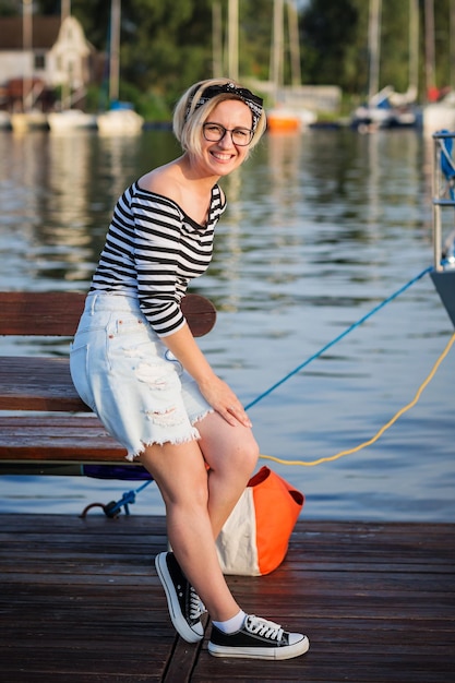 Aantrekkelijke vrouw die zich voordeed op de jachthaven op een zonnige zomerdag aan de rivier