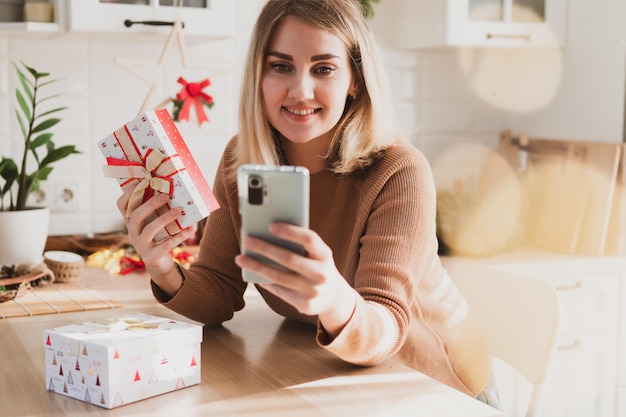 Aantrekkelijke vrouw doet online winkelen op smartphone voor kerstvakantie in haar keuken