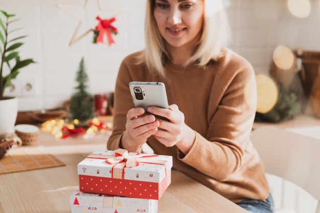 Aantrekkelijke vrouw doet online winkelen op smartphone voor kerstvakantie in haar keuken