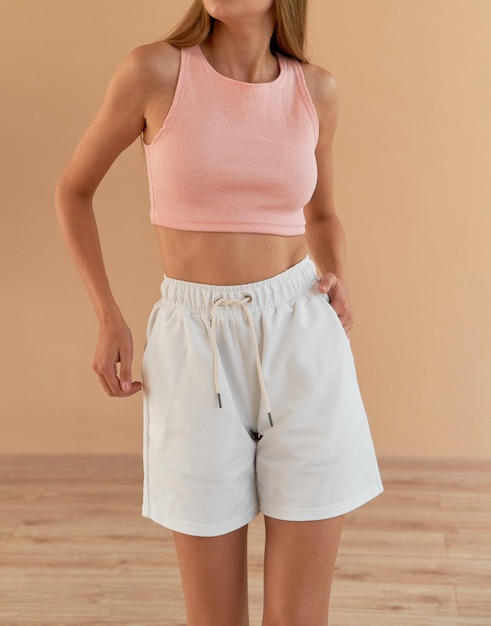 Aantrekkelijke vrouw draagt thuis roze crop top en witte korte broek