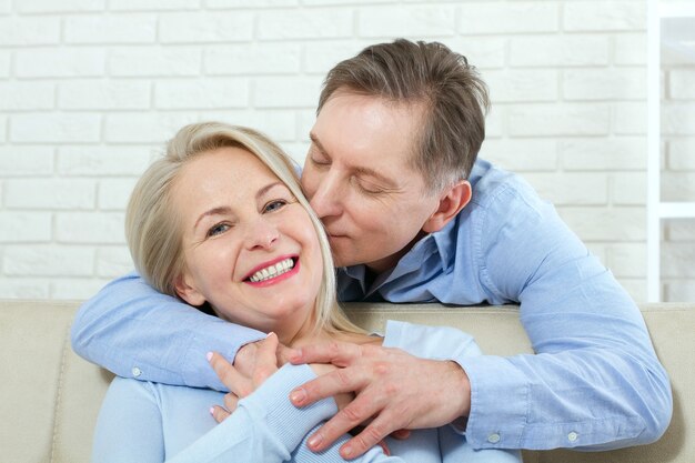 Aantrekkelijke vrouw en man, hij knuffelt haar van achteren en kust op de bank