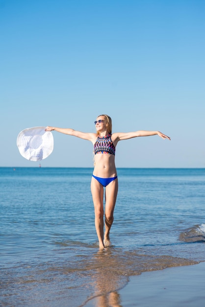 Aantrekkelijke vrouw in bikini die op het strand loopt en plezier heeft