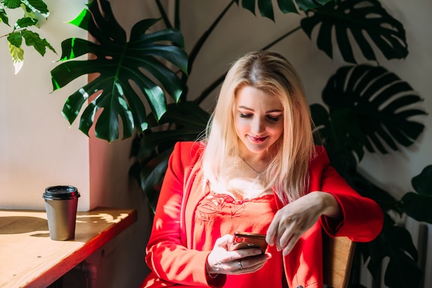 Aantrekkelijke vrouw in een rood jasje praat aan de telefoon