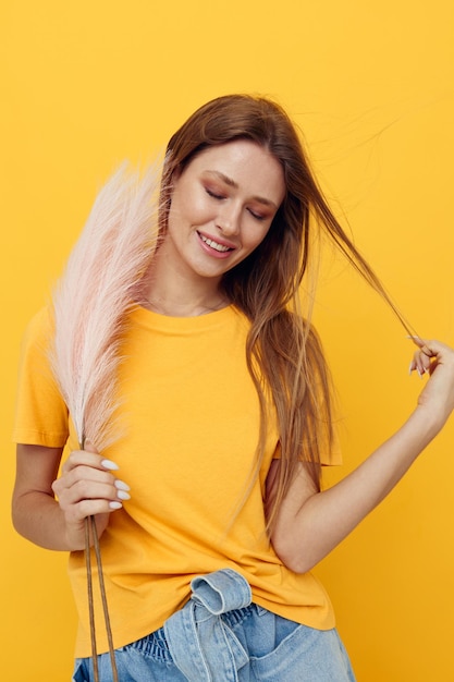 Aantrekkelijke vrouw in gele tshirts roze veren geïsoleerde achtergrond