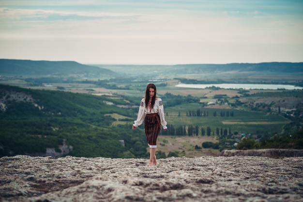 Aantrekkelijke vrouw in traditionele Roemeense kostuum op berg groene onscherpe achtergrond