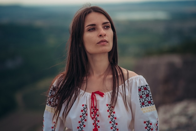 Aantrekkelijke vrouw in traditionele Roemeense kostuum op berg groene onscherpe achtergrond