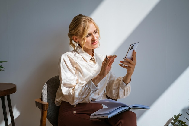 Aantrekkelijke vrouw in zakelijke kleding met daarna een smartphone in haar handen