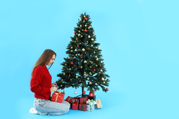 Aantrekkelijke vrouw, kerstboom en geschenkdozen op blauwe achtergrond