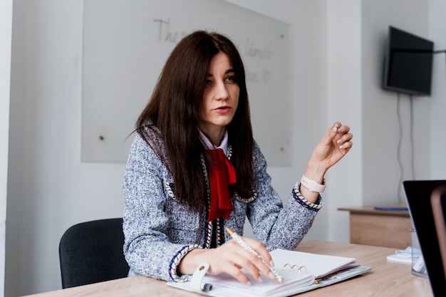 Aantrekkelijke vrouw leraar uitleggen regels in Engelse les. Onderwijs aan de universiteit. Privéstudie op een buitenlandse school met een schoolvrouw. Leraar legt grammatica van moedertaal uit met behulp van laptop.