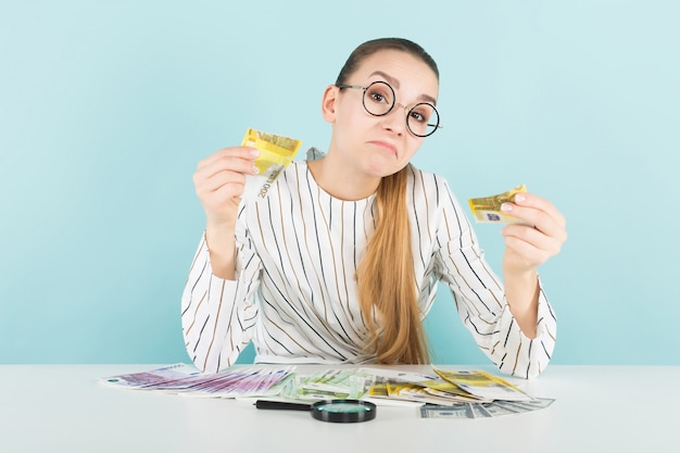 Aantrekkelijke vrouw met contant geld en vergrootglas