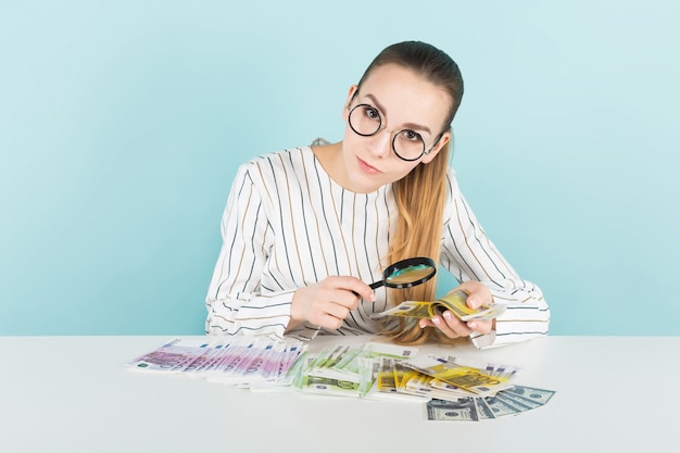 Aantrekkelijke vrouw met contant geld en vergrootglas