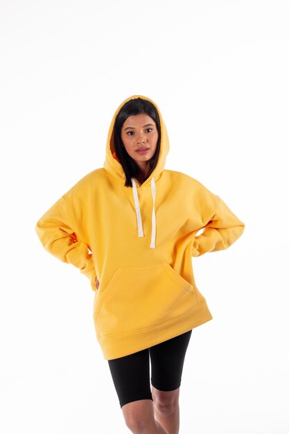 Aantrekkelijke vrouw met een Latijns uiterlijk draagt een gele hoodie op een witte achtergrond Het meisje ziet er sexy en gelukkig uit De elegante brunette draagt een helder sweatshirt Allseason-kleding