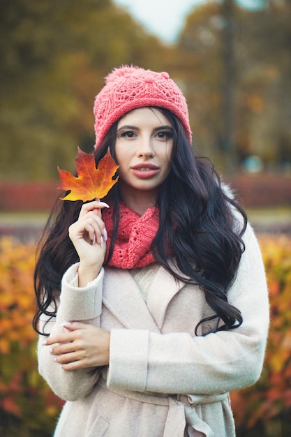 Aantrekkelijke vrouw met herfst esdoornblad buiten in herfst park portret