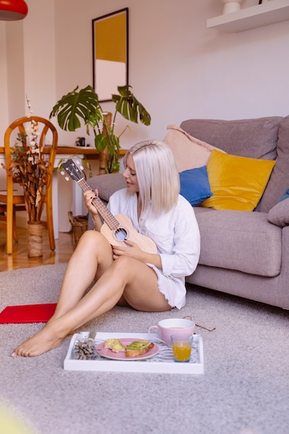 Aantrekkelijke vrouw met lange mannelijke shirt muziek afspelen op de woonkamer in de ochtend