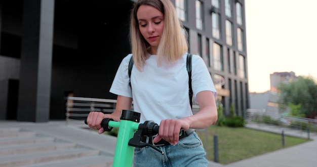 Aantrekkelijke vrouw neemt een elektrische fiets die op straat loopt in de moderne stad