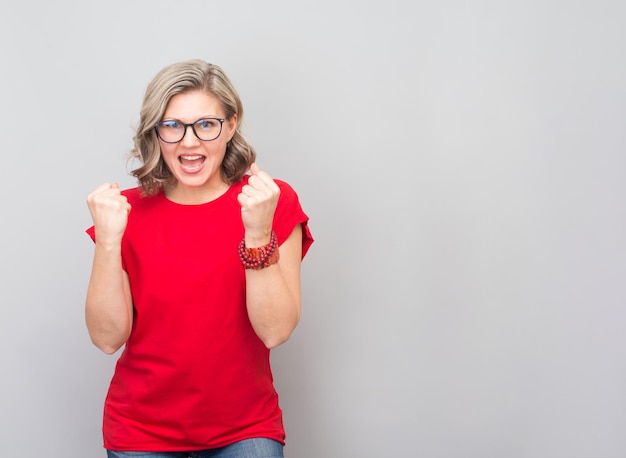 Aantrekkelijke vrouw van middelbare leeftijd erg blij en opgewonden winnaar gebaar te doen met opgeheven armen glimlachend en schreeuwend voor succes Winnaar en viering concept