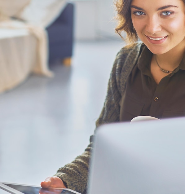 Aantrekkelijke vrouw zit aan een bureau met een kopje koffie