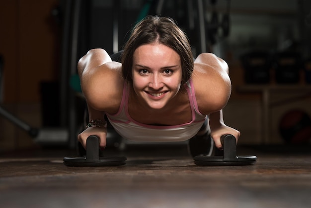 Aantrekkelijke vrouwelijke atleet die pushups op de vloer uitvoert