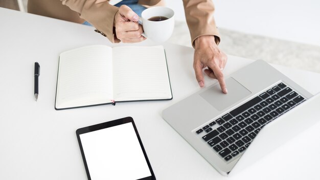 Aantrekkelijke vrouwen in casual business zitten aan een tafel aan het werk op haar laptop computer thuis kantoor voor een raam.