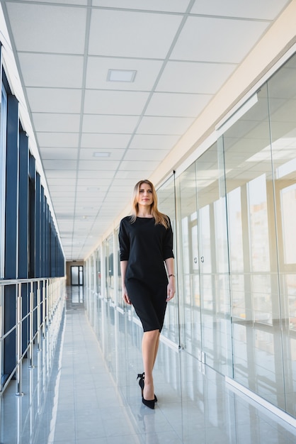 Aantrekkelijke zakelijke vrouw met een zwarte jurk op kantoor