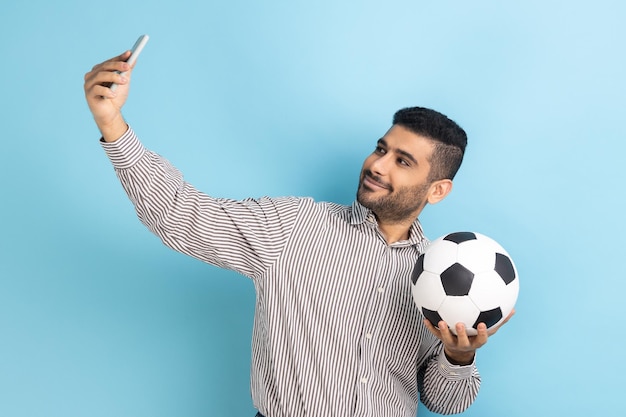 Aantrekkelijke zakenman die selfie maakt met videogesprek of livestream uitzendt met bal in de hand