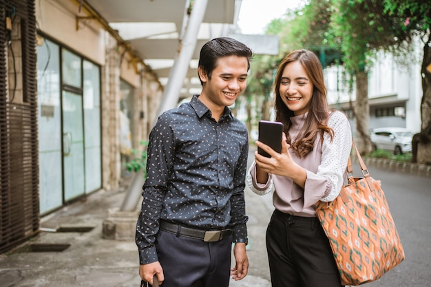 Aantrekkelijke zakenvrouw die het scherm van haar mobiele telefoon laat zien aan haar partner