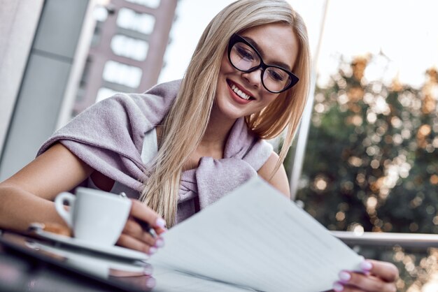 Aantrekkelijke zakenvrouw die kranten leest in het stadscafé