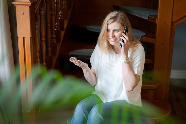 Aantrekkelijke zakenvrouw die vanuit huis werkt en smartphone gebruikt voor communicatie en conversatie...