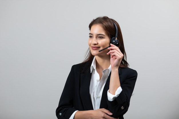 Aantrekkelijke zakenvrouw in pakken en headsets lacht terwijl ze werkt isoleren