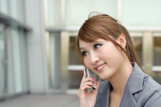 Aantrekkelijke zakenvrouw met behulp van mobiele telefoon, close-up portret van halve lengte binnen buiten moderne gebouwen.